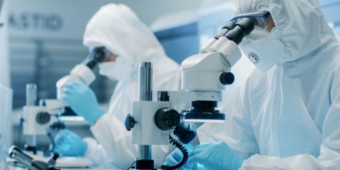 科学家们穿着防护服使用显微镜